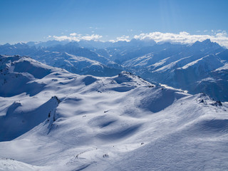 Panoramic view down snow covered valley in alpine mountain range with coniferous pine trees and clouds. Meribel, France, 2018