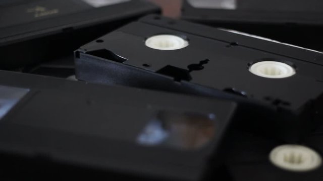 Take a vhs cassette tape from a stack of tapes and put it again on place