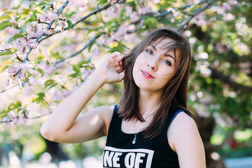 Fototapeta premium Woman near sakura blooming tree. Girl on blooming cherry-tree background. Spring concept