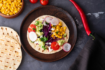 Pulled pork tacos with red cabbage, tomatoes, corn, feta and avocados overhead shot.