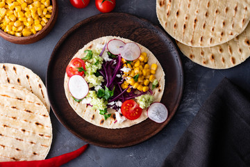 Pulled pork tacos with red cabbage, tomatoes, corn, feta and avocados overhead shot.