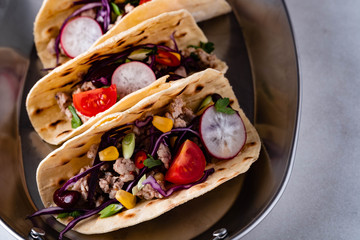Corn tortillas with grilled chicken fillet, guacamole sauce on white table.