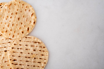 Stack of homemade whole wheat flour tortilla, on white background.