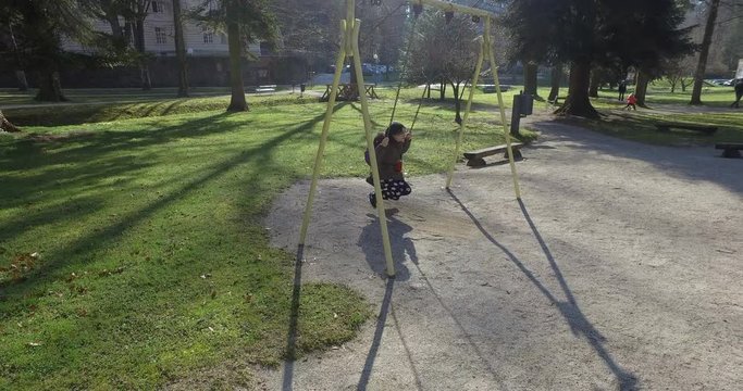 Bambina in un parco si diverte sull'altalena