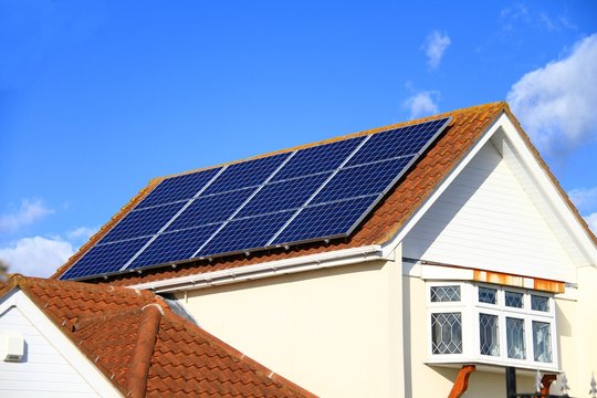Solar panel on top of a roof with blue sky in the background no people stock photo