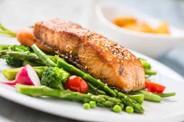 Roasted salmon steak with asparagos broccoli carrot tomatoes radish green beans and peas. Fish meal with fresh vegetable