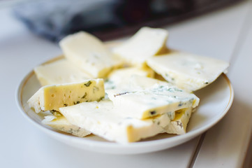 cheese with mold chopped lying on a plate, close-up