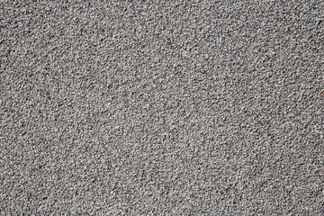 Fototapeta premium Grey background made of very small pebble evenly spread around the wall. Small stones are almost of the same size and make a perfectly even surface