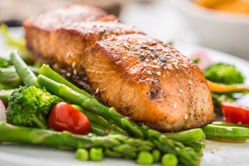 Roasted salmon steak with asparagos broccoli carrot tomatoes radish green beans and peas. Fish meal with fresh vegetable