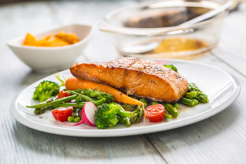 Roasted salmon steak with asparagos broccoli carrot tomatoes radish green beans and peas. Fish meal with fresh vegetable