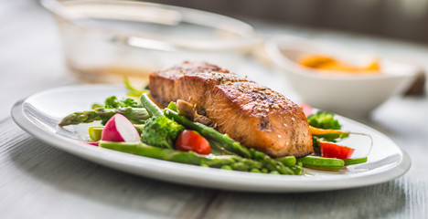 Roasted salmon steak with asparagos broccoli carrot tomatoes radish green beans and peas. Fish meal with fresh vegetable