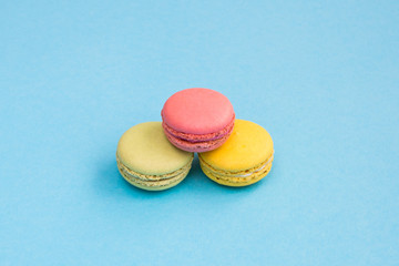Colorful macaroons, pink, yellow and green macaroons on blue background. Bright and color concept. Copyplace, place for text.