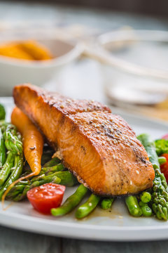 Roasted salmon steak with asparagos broccoli carrot tomatoes radish green beans and peas. Fish meal with fresh vegetable