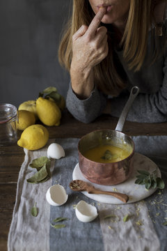 Woman testing lemon cream in saucepan