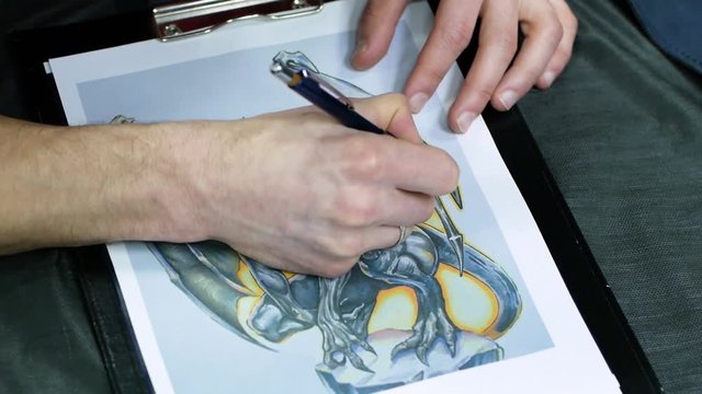 Tattoo master draw picture of dragon, tattooer work in studio