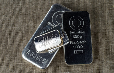 Several different silver bars against the background of the texture of coarse cloth..