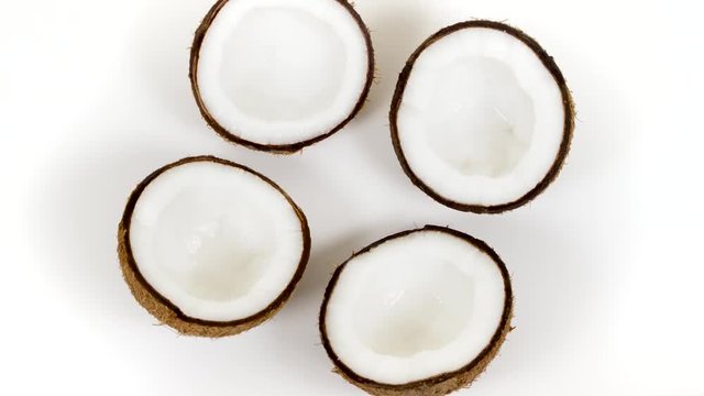 Top view of four ripe tropical coconut halves with yummy white pulp rotating on white isolated background. Healthy fresh tropical fruits. Loopable seamless cocos rotating
