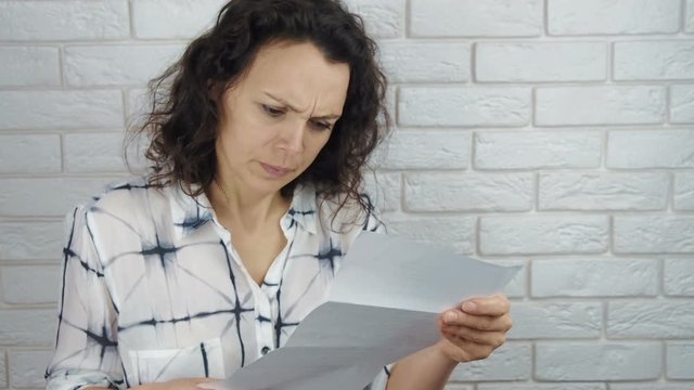 A woman is reading a letter. A frustrated woman with a letter.