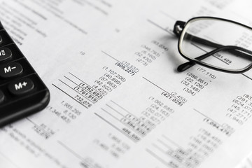 Investment and Financial analysis and reporting concept, Calculator and eyeglasses lying on financial performance report. focus in center.