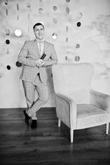 Handsome man in gray suit with microphone against chair background on studio.  Laughs face of toastmaster and showman.
