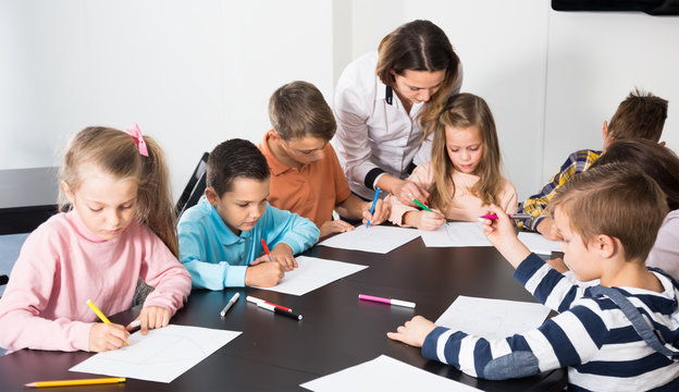 satisfied little children with teacher drawing in classroom
