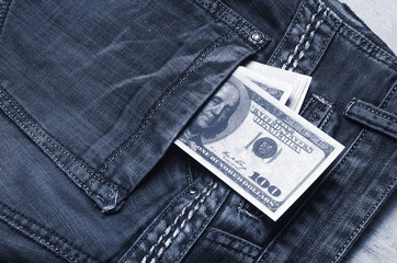 Banknotes of a hundred dollars with a portrait of Franklin peep out of the pocket of jeans trousers. Money in your pocket, cash savings, pocket expenses. The last money, the crisis.