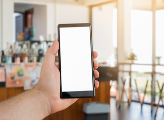 Closeup hand holding mobile  phone or smartphone in coffee shop