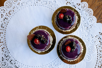 Three little violet cakes with raspberry and blackberries under glaze