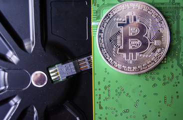 Silver souvenir coin Bitcoin on computer circuit board background.