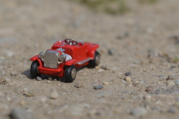 Small red oldtimer toy car on driving on a lane outdoor