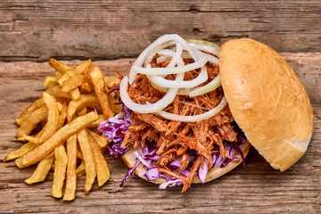 Barbeque Pulled pork Sandwich with BBQ Sauce,salad with red cabbageonion,Sauce and Fries on wooden background,Fast food