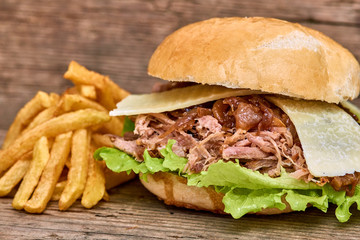 Barbeque Pulled pork Sandwich with green salad,caramelized onion,cheese,Sauce and Fries on wooden background,Fast food