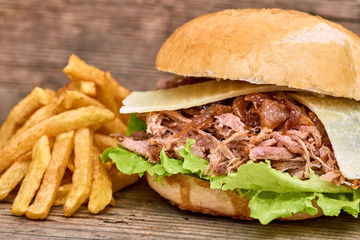 Barbeque Pulled pork Sandwich with green salad,caramelized onion,cheese,Sauce and Fries on wooden background,Fast food