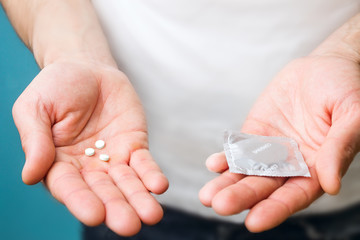 Male contraceptives. Pills and condom in the hands of men