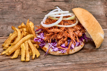 Barbeque Pulled pork Sandwich with BBQ Sauce,salad with red cabbageonion,Sauce and Fries on wooden background,Fast food