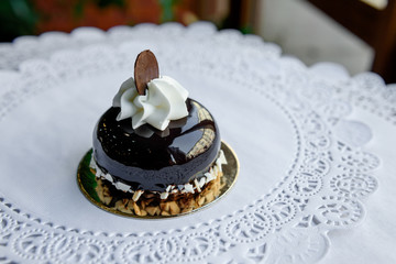 Little brown  cake with white glase and slice of chocolate on top of it