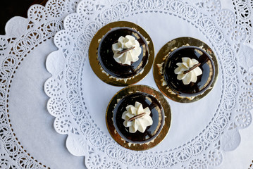 Look from above at three little brown cakes with white cream and slice of chocolate on top of them