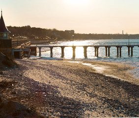 Pier in the sea at sunset. Promenade and sea pier in the rays of the rising sun. The sea coast...