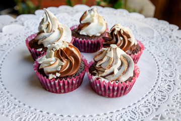 Five tasty cupcakes with white and caramel cream on top