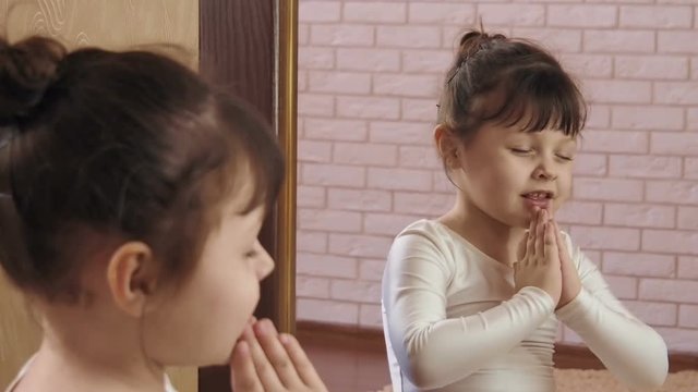 The child prays. A beautiful little girl prays.