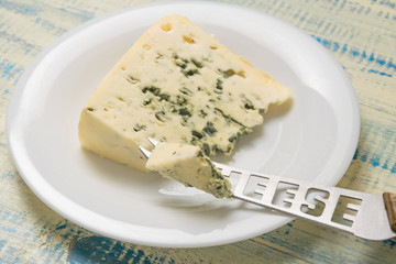 Cheese blue with mold on a plate with a knife.