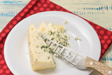 Blue cheese and a knife with the inscription cheese on a plate.