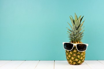 Hipster pineapple with trendy sunglasses against turquoise background. Minimal summer concept.