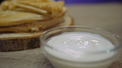 Obraz na płótnie Canvas Pancake in sour cream. Damn dipped in sour cream. Sour cream and pancakes.