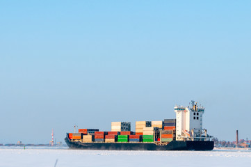 laden container ship goes along sea channel among ice