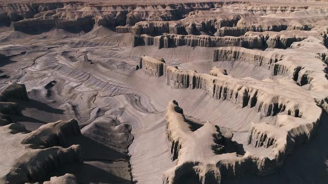 Aerial view flying over the Caineville Desert in Utah viewing maze of jagged cliffs across the landscape.