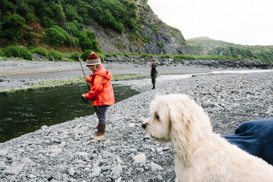 Young girl fishing with her father and dog