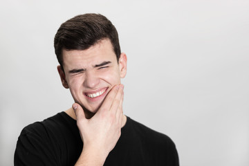 Young man suffering from toothache on white background