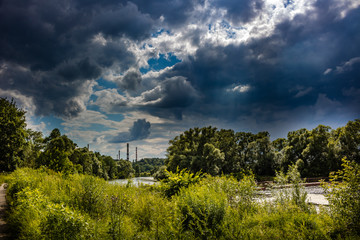 Dark clouds over the river valley and pipes boiler house in the background
