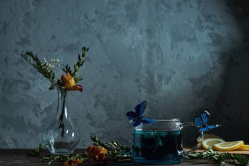           Still life, on the table is tea, flowers and butterflies fly